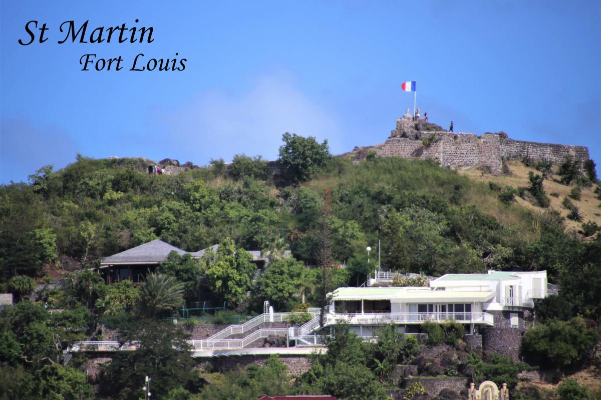 De top van het Fort Louis steekt boven de groene heuvels uit, met een wapperende Franse vlag.