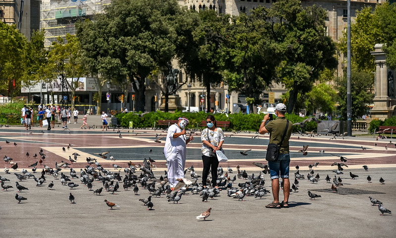 Een toeriste poseert bij een mimespeler tussen de duiven op het plein.