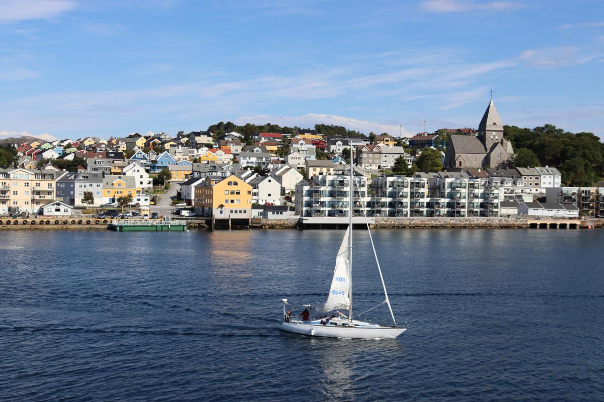 Zeilboot op zee, met op de achtergrond de stad Kristiansund.