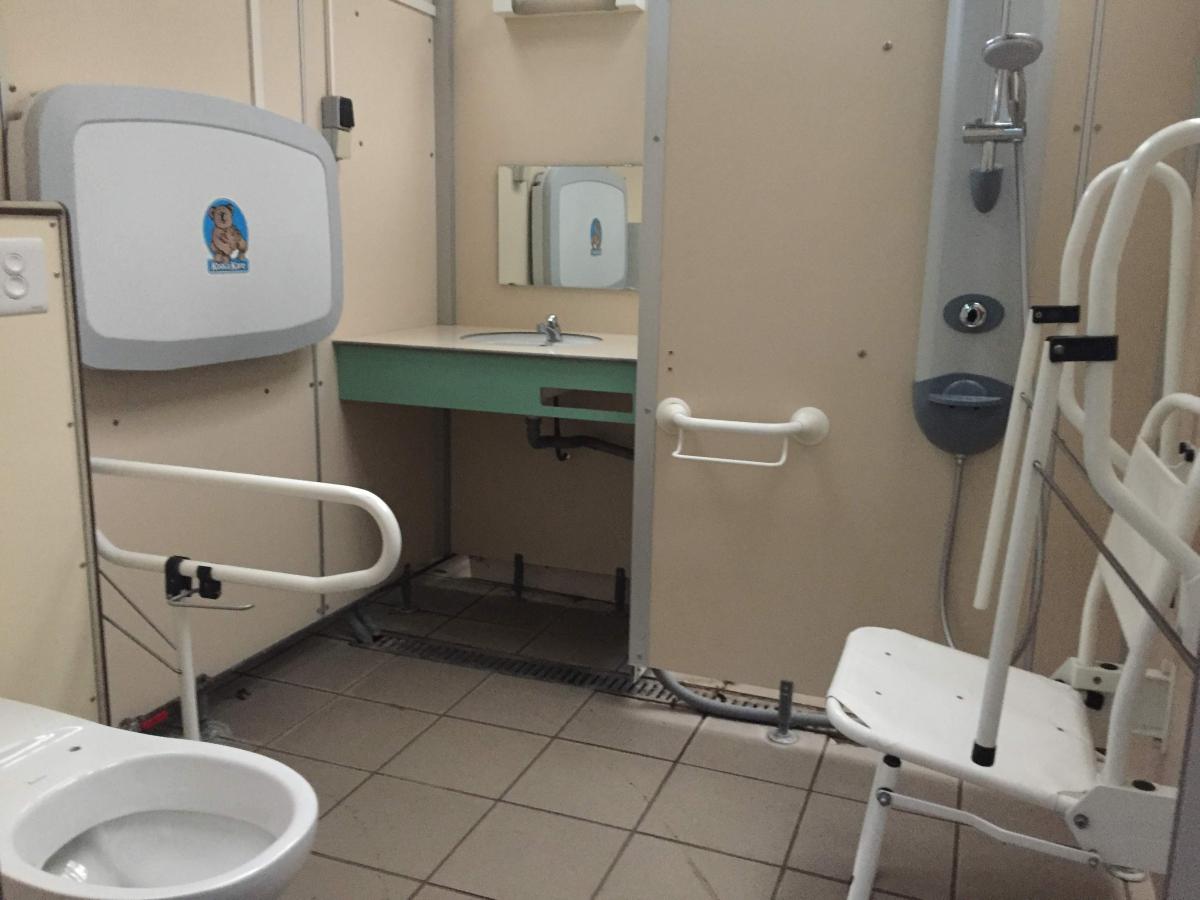 Foto van het sanitair blok (interieur). Het toilet heeft een steunbeugel. Er is een douche met douchestoel en de sproeikop is afneembaar.