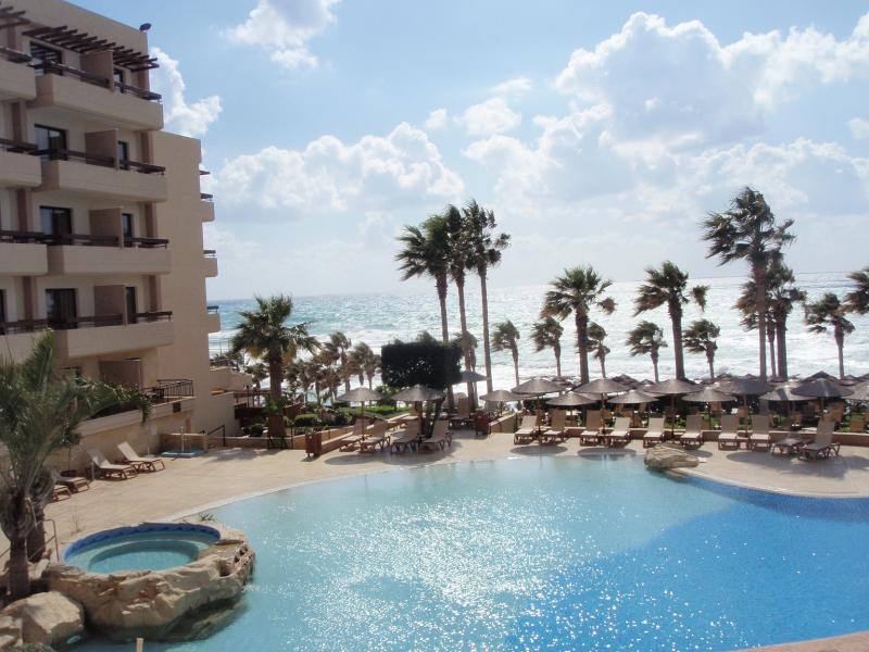 Uitzicht van het hotel, over het zwembad en de palmbomen.