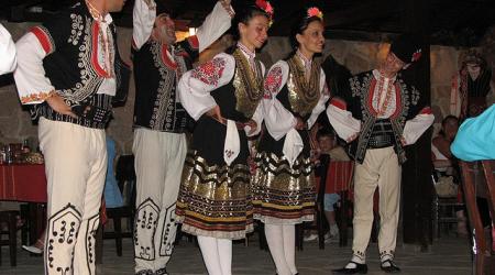 Dansers in traditionele Bulgaarse kleding buigen voor hun publiek.