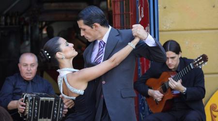 Begeleid met gitaar en bandoneon dansen een man een vrouw de tango in Buenos Aires.