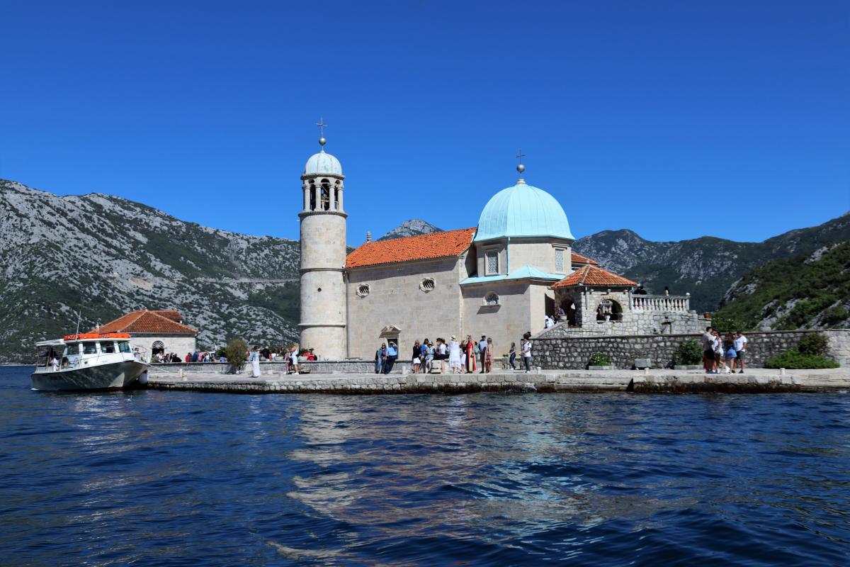De Onze-Lieve-Vrouwkerk, met pastelblauwe koepeldaken, ligt vlak aan het water.