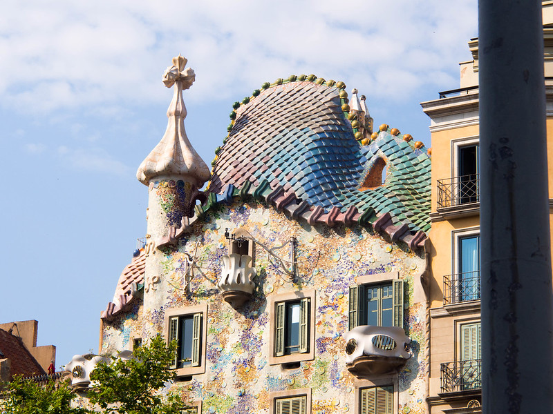 De veelkleurige voorgevel en de paarlemoer-achtige kleuren op het dak versterken de sprookjesachtige sfeer van dit huis van Gaudi.