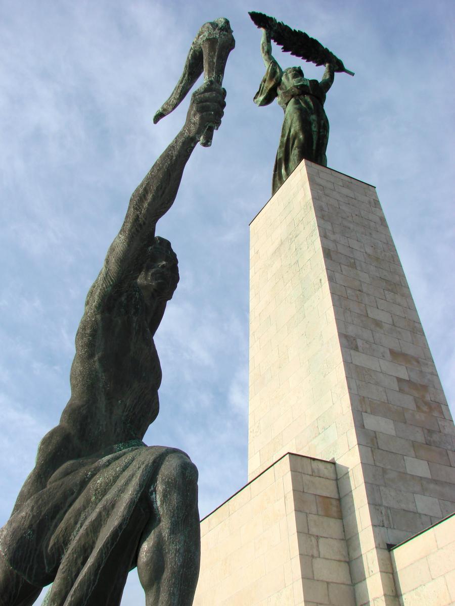 Vrijheidsbeeld met een figuur met een fakkel en een andere met een grote veer in de handen.