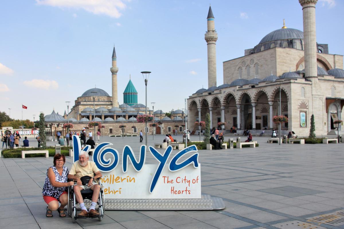 Jozef en Marie-Claire bij een bord van Konya. Achter hen de moskee en het klooster (Tekke).