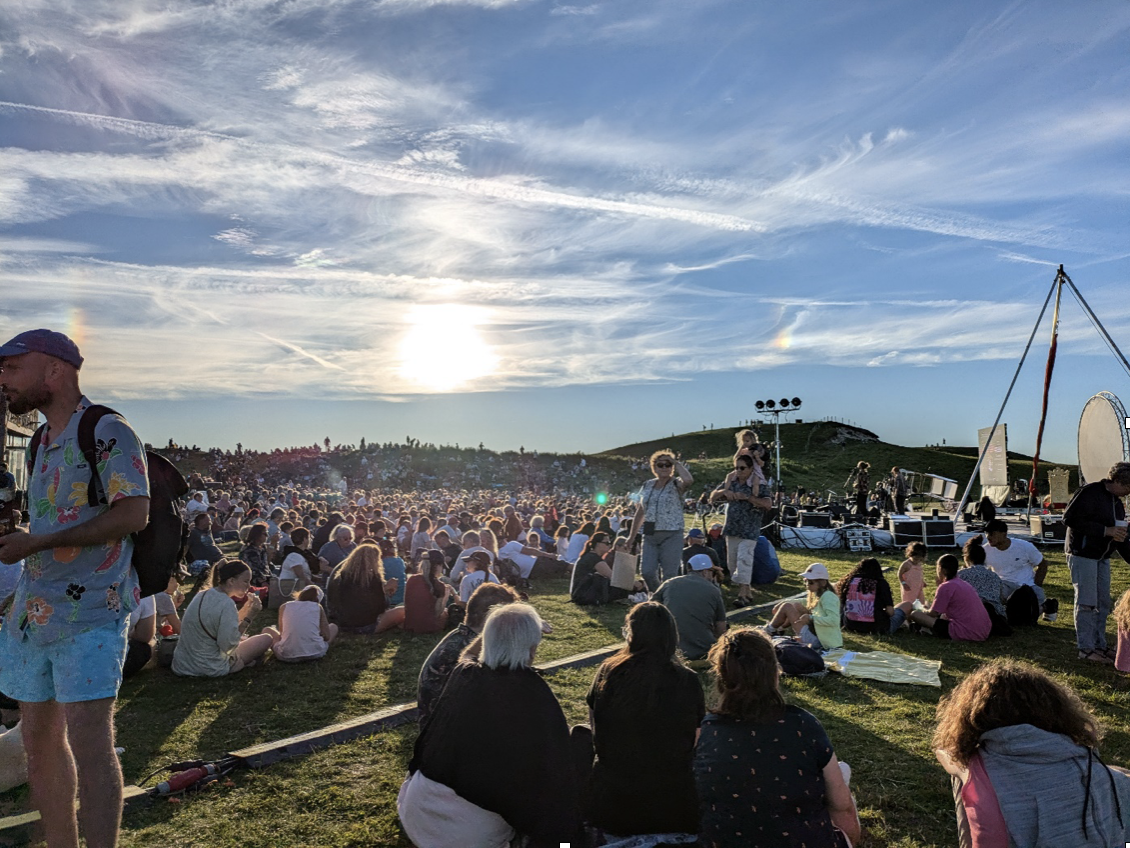 Zomeravond. Een massa mensen wacht zittend op het gras tot de avondshow begint.