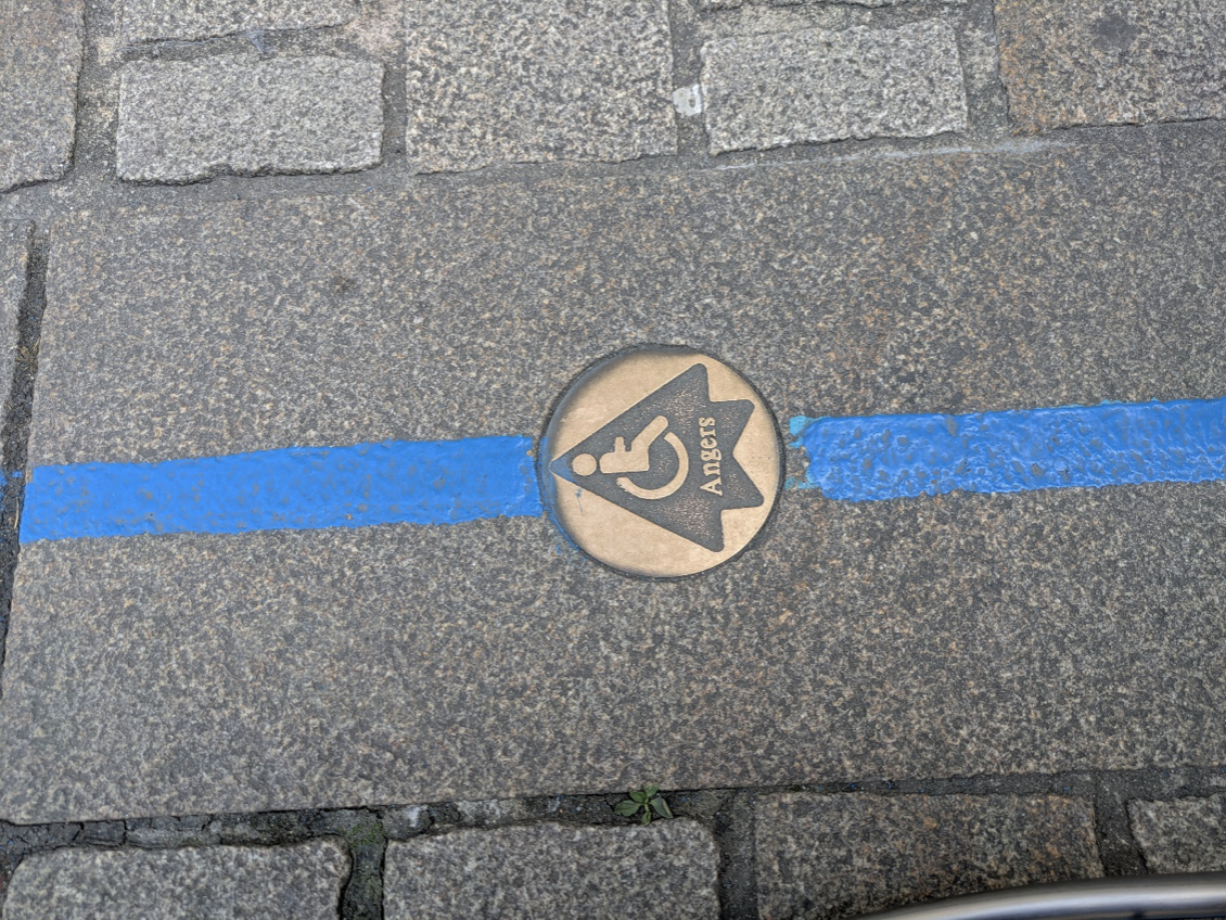 De route is op de straatstenen geschilderd en gemarkeerd door een schildje met rolstoellogo en een pijl.