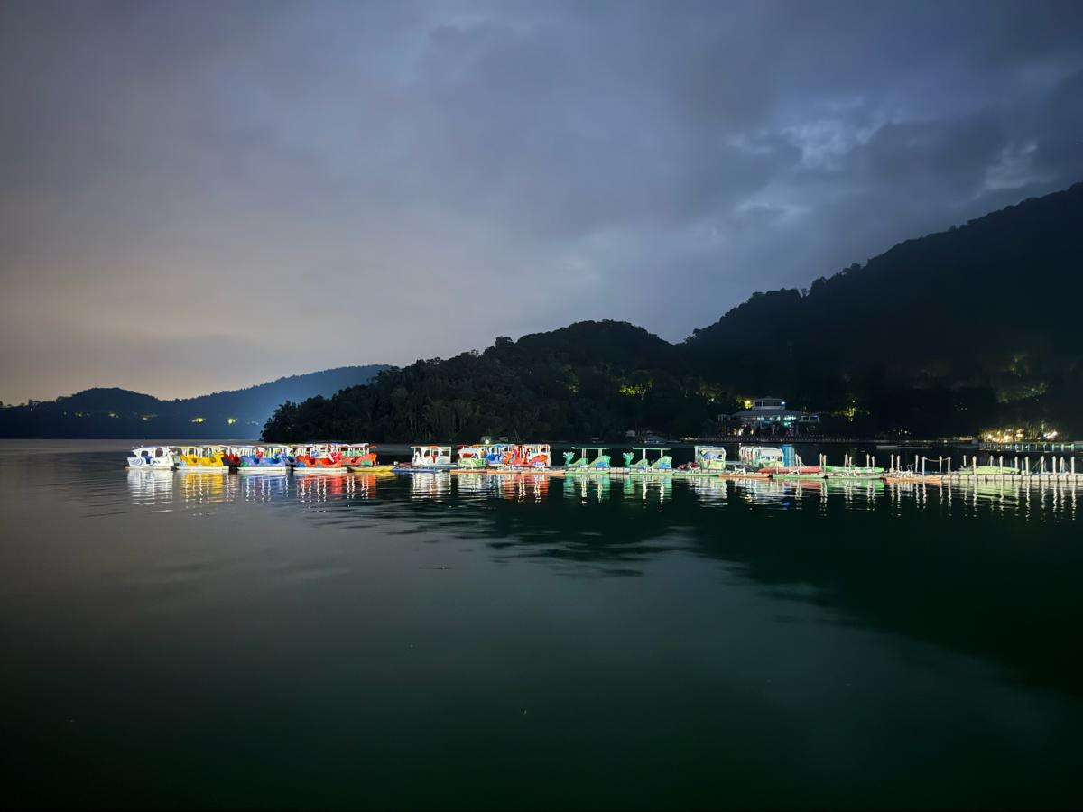 Kleurig verlichte plezierboten rusten op het meer bij valavond.