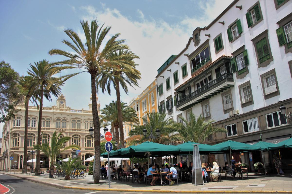 Een terras, palmbomen en koloniale gebouwen rond het Columbusplein.