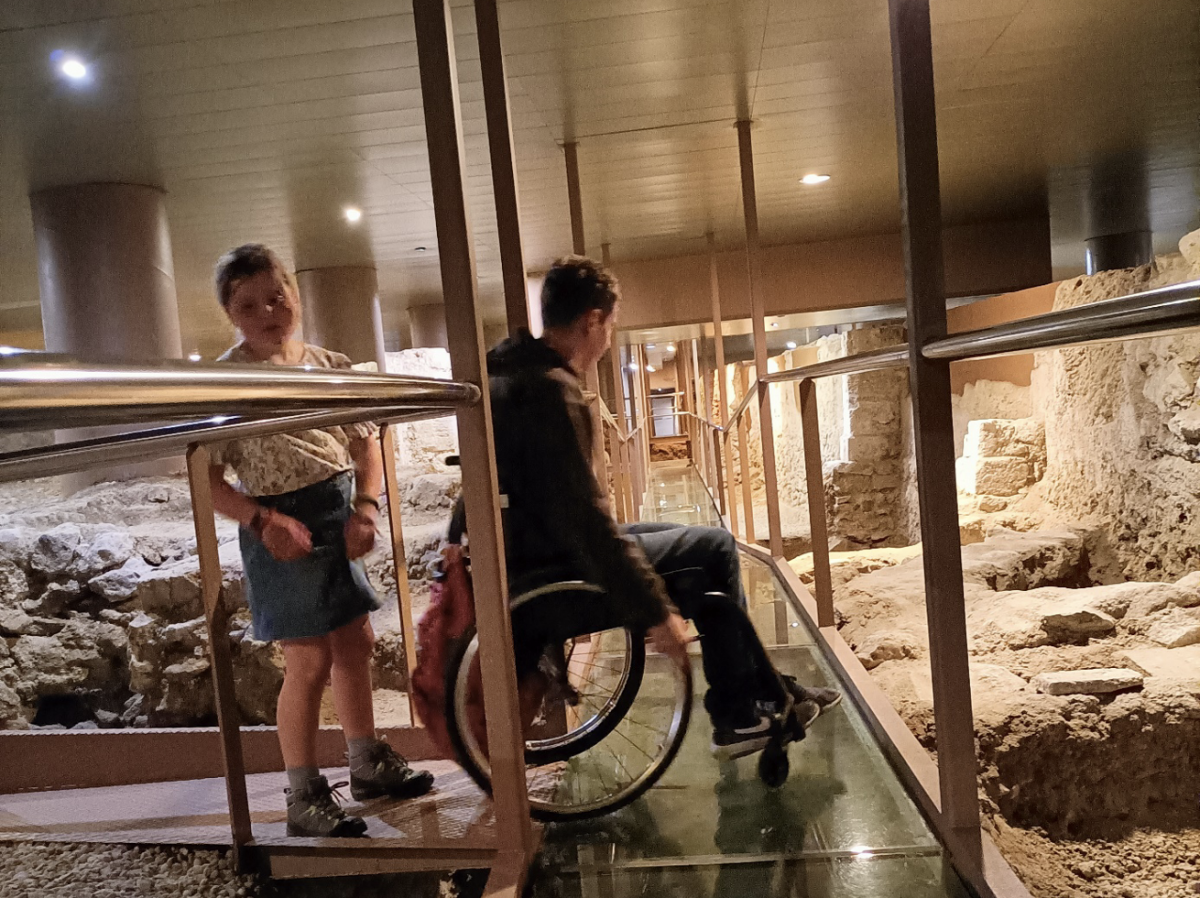  vader en zoon verkennen de opgravingen van de oude stadsmuren via een deels doorzichtig pad.