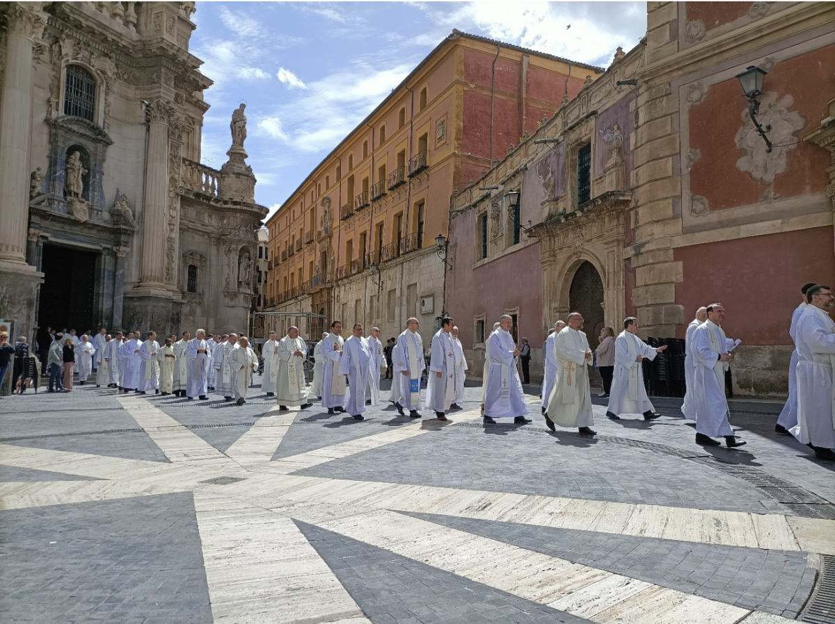 Processie van tientallen geestelijken in witte gewaden.
