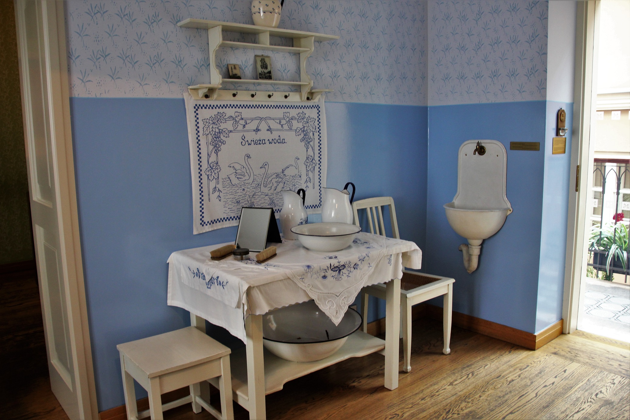 Wadowice, geboortehuis Johannes-Paulus II - Woonkamer met blauwe muren, witte meubels en een houten vloer.