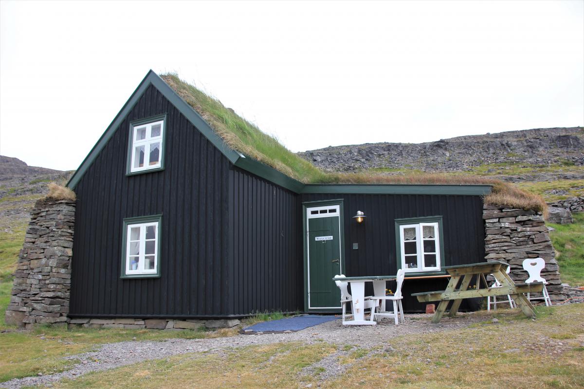 De turfboerderij is een zwartgeschilderd houten gebouw met gras op het dak.