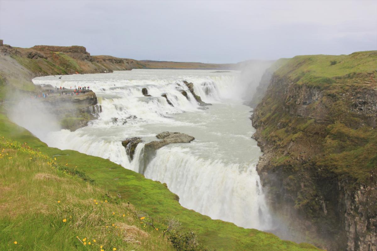 Een groepje mensen bij de waterval tonen hoe reusachtig Gullfoss wel is.