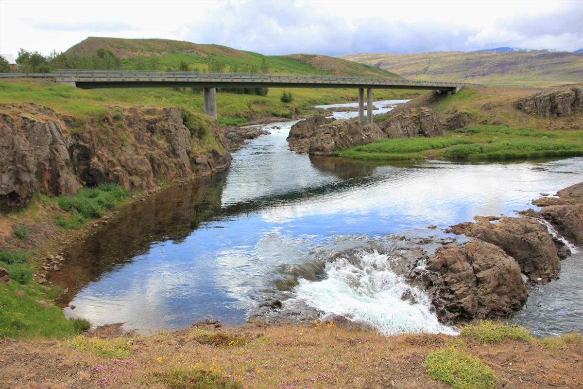 Waterval met bergrivier onder een brug.