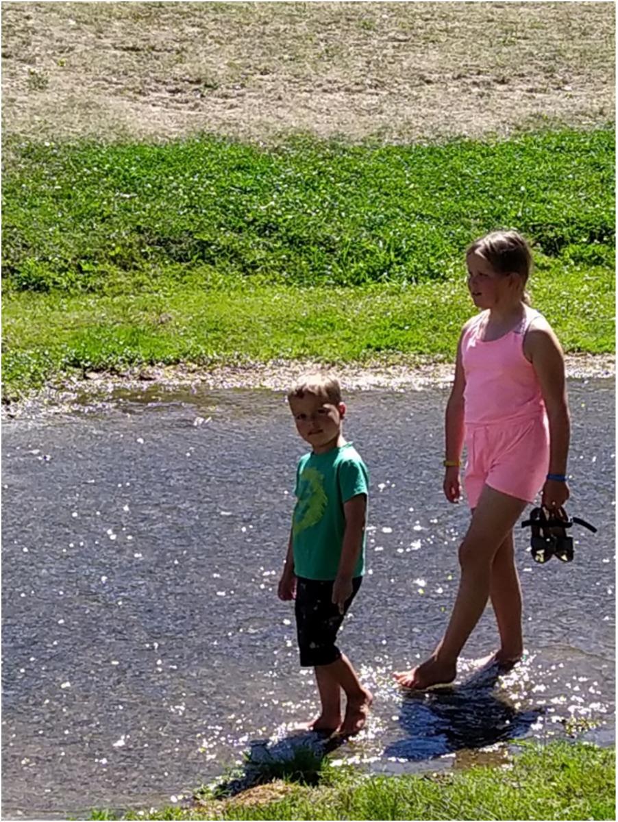 Kinderen pootjebadend in het zijriviertje.