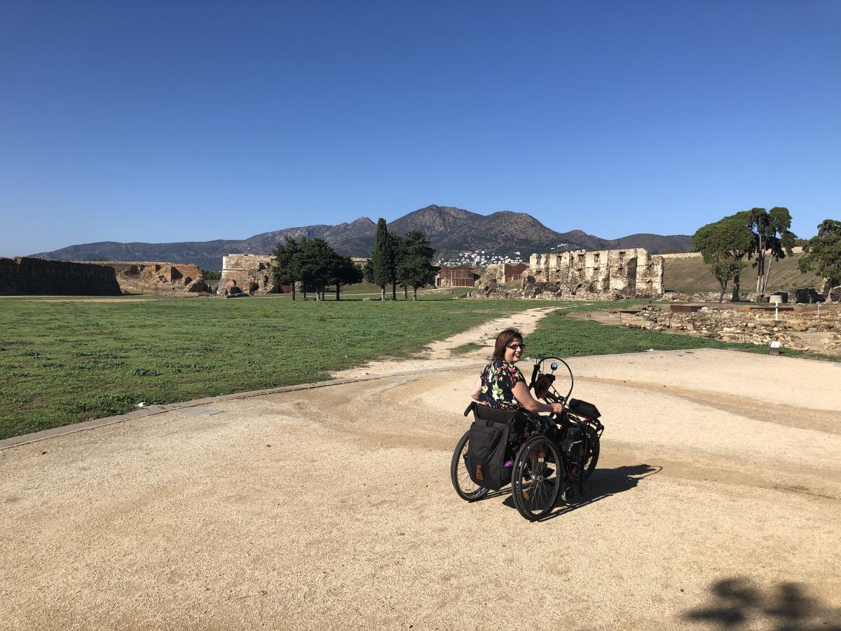 Vanja met de handbike voor de citadel. Er ligt een groot grasveld voor de oude muren.