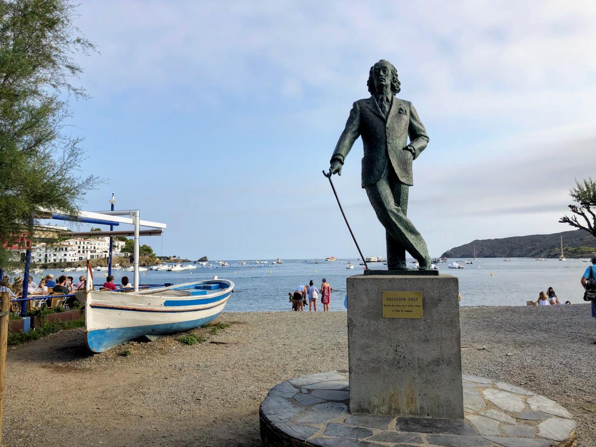 Standbeeld van schilder Salvador Dali, met wandelstok. Op de achtergrond de baai van Figueres.