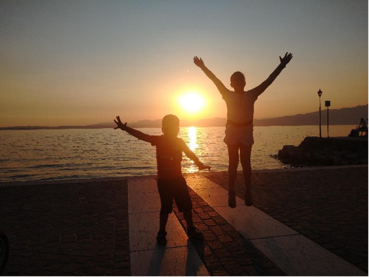 Vakantiepret bij zonsondergang. Broer en zus poseren uitbundig bij het meer.