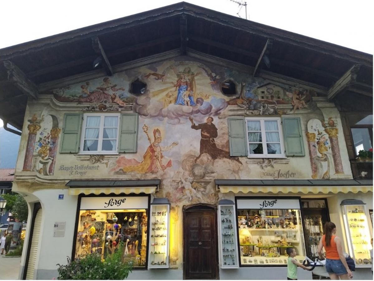 Souvenirwinkel (Bayerische Volkskunst, staat er) met opvallend beschilderde voorgevel met religieuze taferelen.