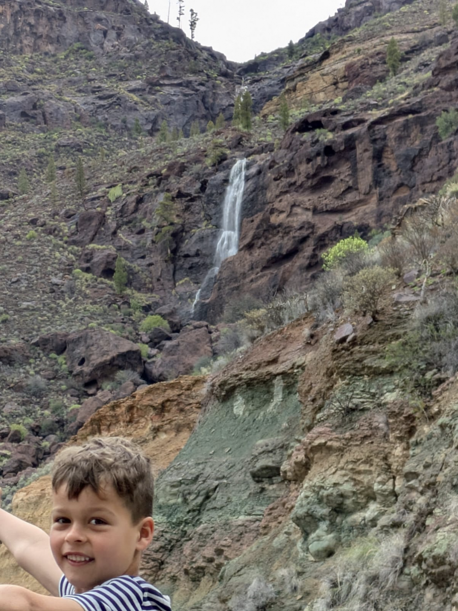 Jona wijst vol verbazing naar een waterval die van hoog naar beneden stroomt.