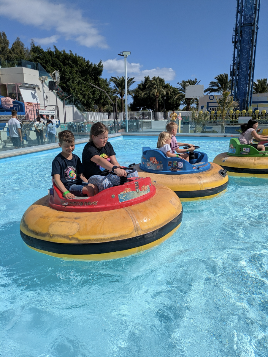 Kinderen varen rond in een soort botsauto's op het water.