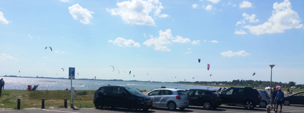 Een zonnige hemel vol grote vliegers (de kitesurfers).