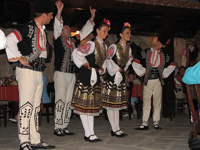 Dansers in traditionele Bulgaarse kleding buigen voor hun publiek.