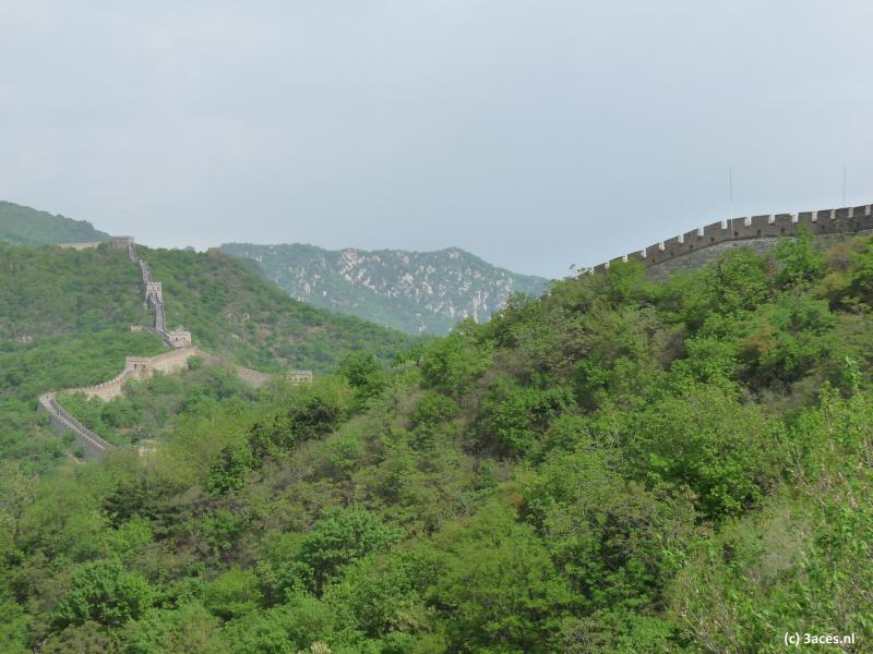 De Chinese Muur kronkelt tot ver voorbij de horizon door de groene heuvels.