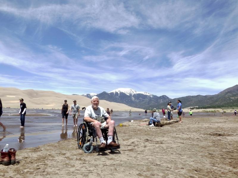 Jozef op de zandvlakte van Great Sand Dunes National Park. Aan de horizon ligt eeuwige sneeuw op een bergtop.