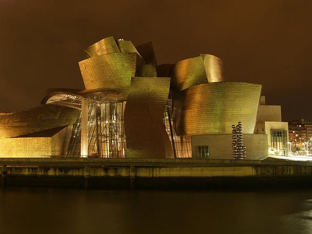 Het grillige gebouw van het Guggenheim museum schittert als goud in de avondzon.