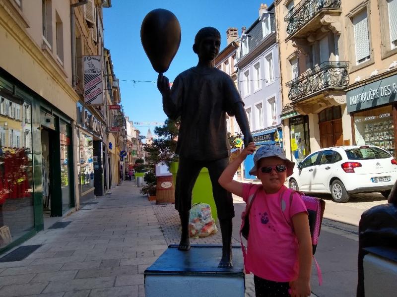 Dochtertje poseert bij een standbeeld in Sarrebourg