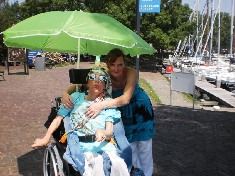 Klaartje en Heidi, moeder en dochter, genieten van de schaduw onder een parasol.