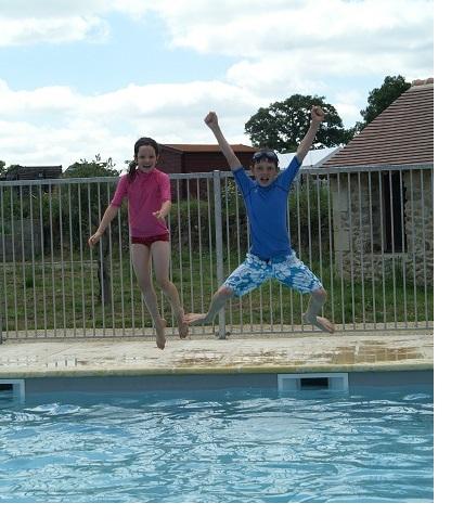 Twee kinderen springen uitgelaten in het water.