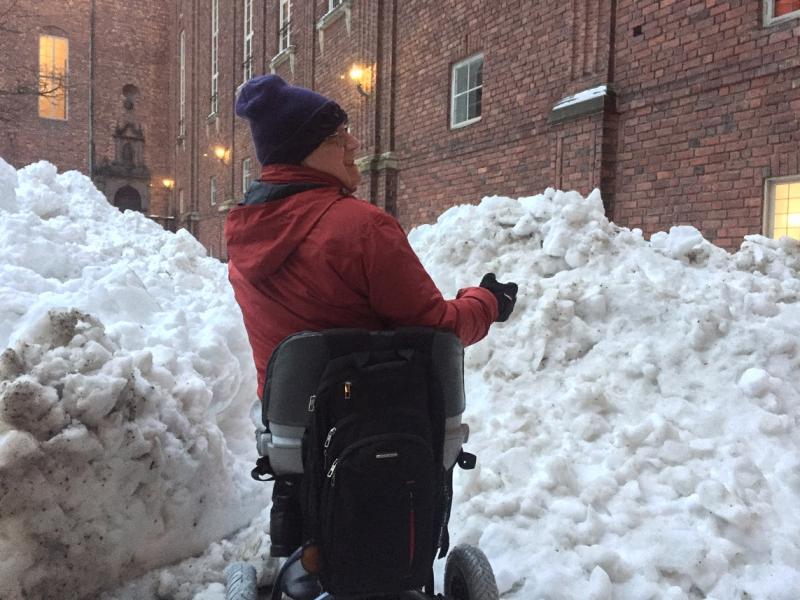 Rik met zijn scootmobiel midden in de sneeuw, die tot op ooghoogte komt.