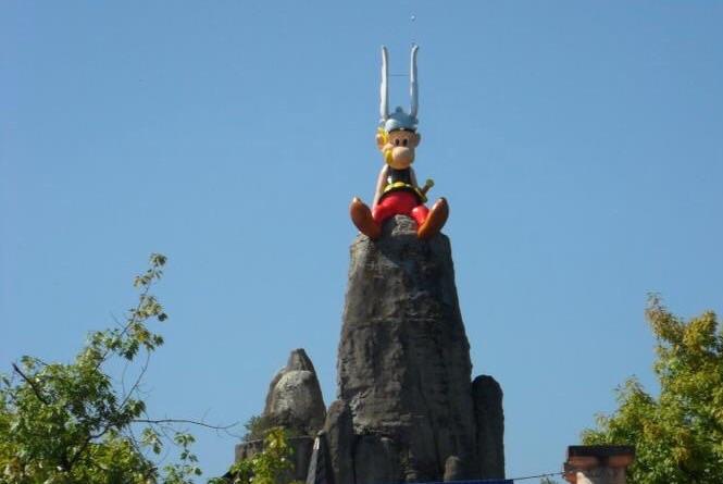 Asterix kijkt gezeten op een reuze menhir over het park.