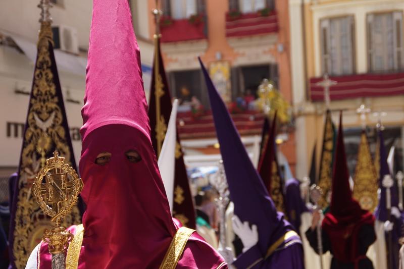 Een deelnemer aan een traditionele boeteprocessie kijkt ons aan. Hij of zij draagt een hoge puntmuts.