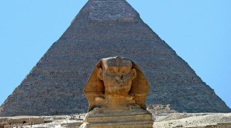 Voor een piramide rust een metershoge sfinx, een leeuw met mensenhoofd.