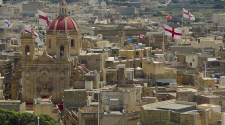 Zicht op de stad, met veel Maltese vlaggen en de rode dakkoepel van de kathedraal van Gozo.